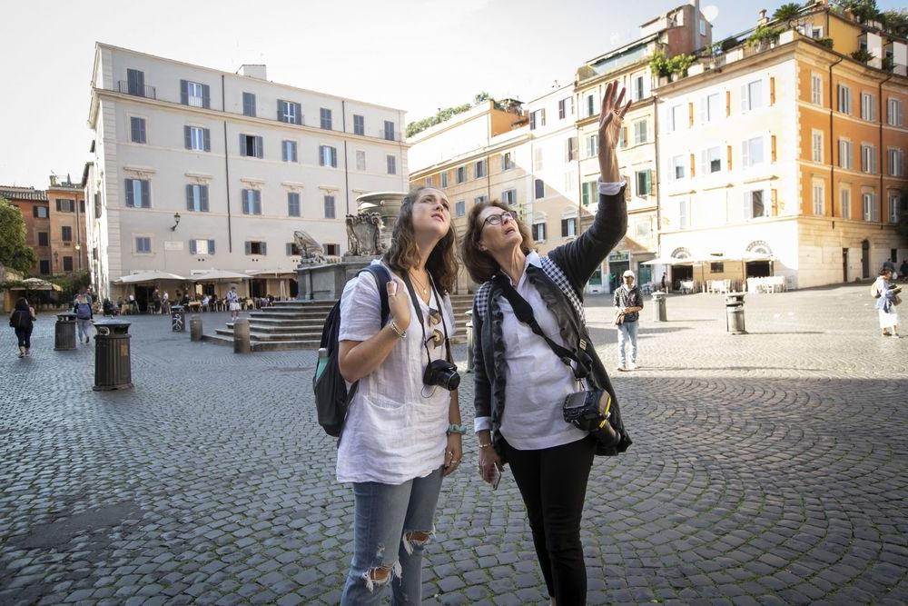 在意大利的一个广场上，一名教授和一名学生脖子上挂着相机观察周围的环境.